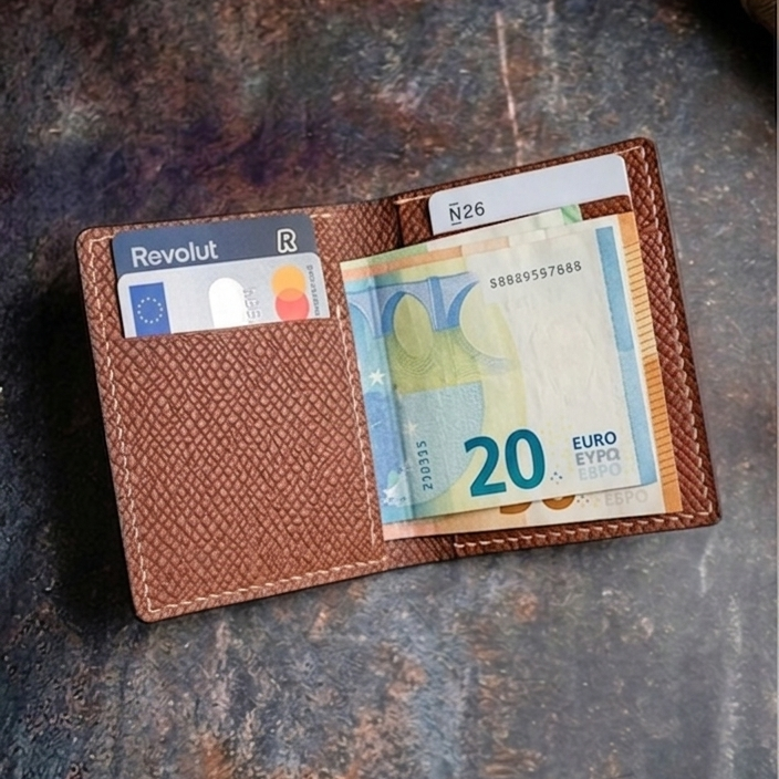 Brown leather wallet with cards and a 20 Euro bill on a textured dark surface